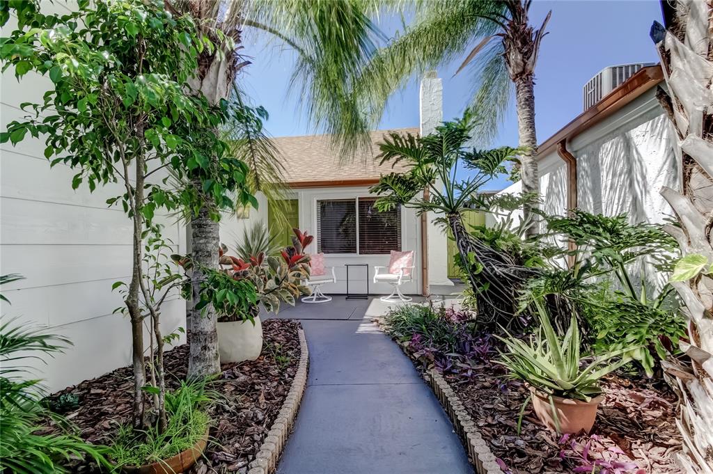 A paved walkway leads to a small patio with two chairs in front of a house — 12625 SHELL POINT DRIVE, HUDSON, FL