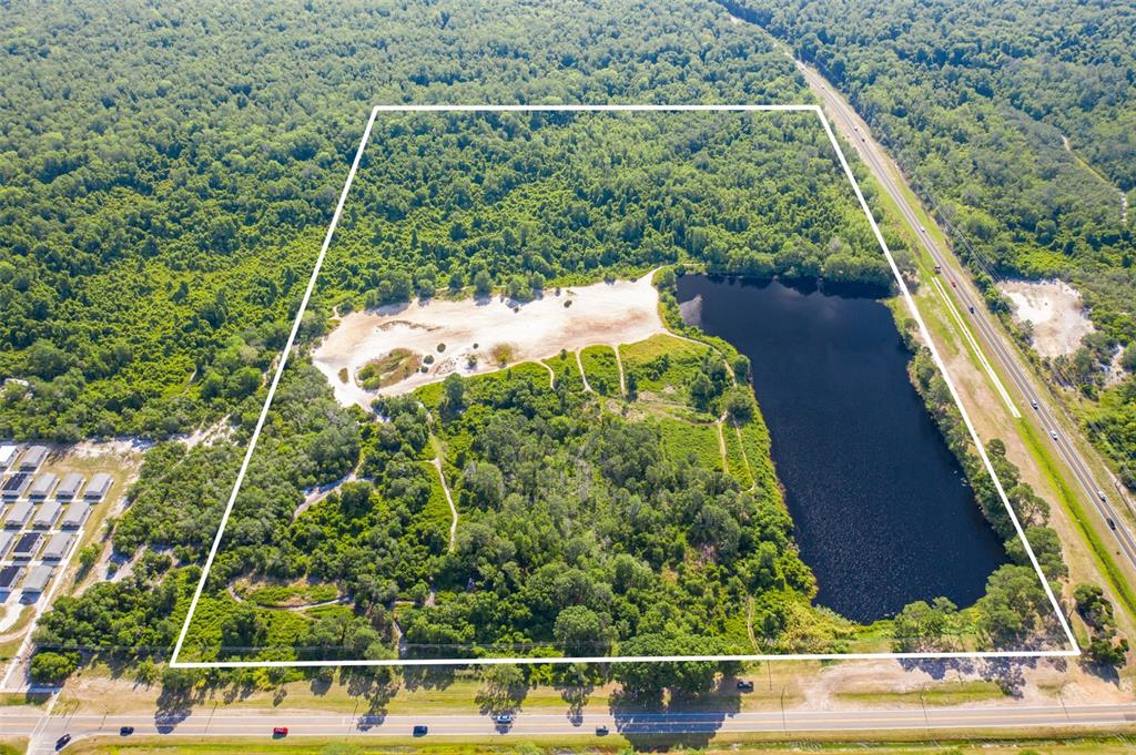 An aerial view shows a large, wooded plot of land featuring a lake and sandy clearing — LAUREL AVENUE, KISSIMMEE, FL