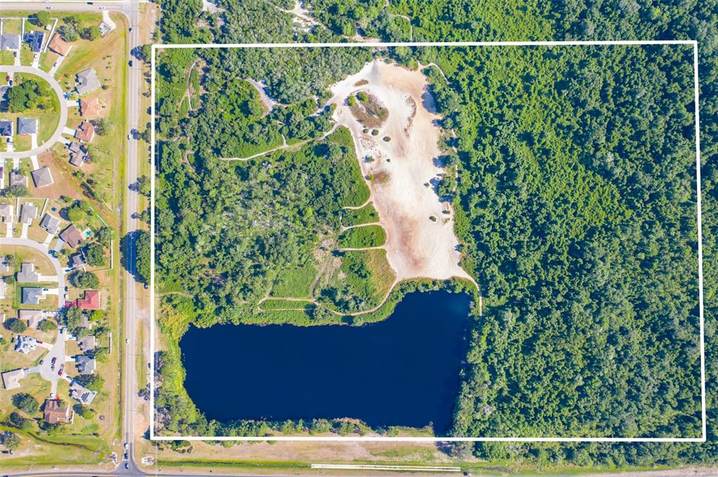 An aerial view shows a rectangular plot of land featuring a pond and sandy clearing — LAUREL AVENUE, KISSIMMEE, FL