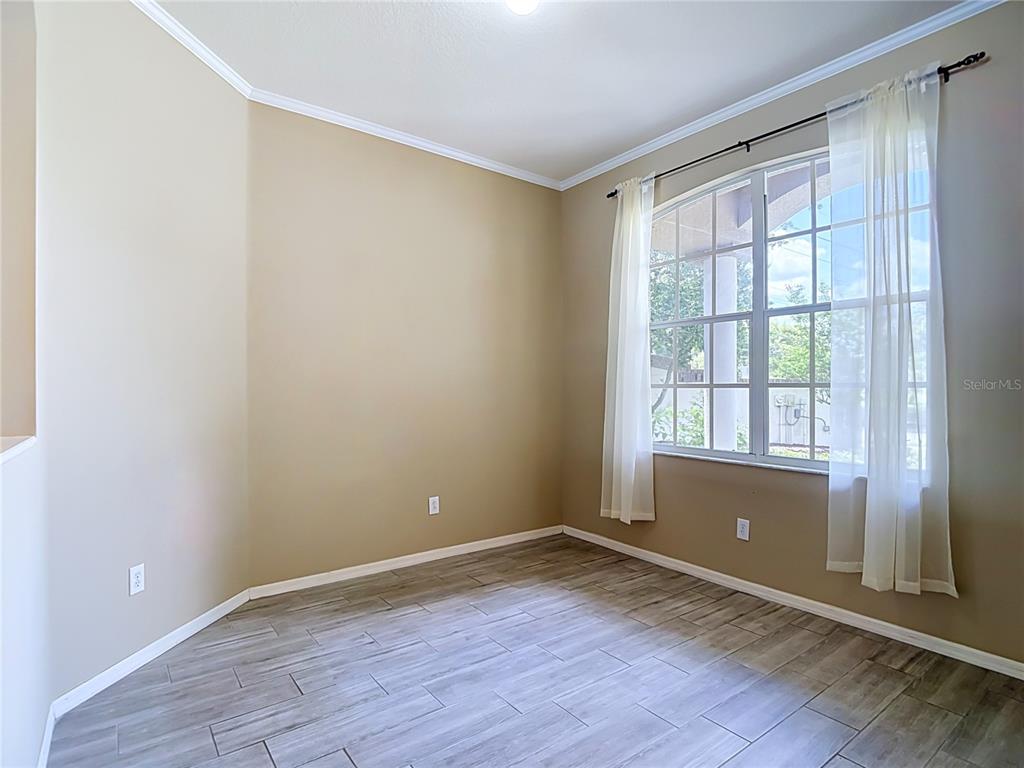 An empty room features beige walls, wood-look tile flooring, and a window with white curtains — 2866 DUNCAN TREE CIRCLE, VALRICO, FL