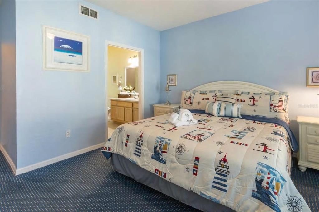A bedroom with light blue walls, a nautical-themed bedspread, and an attached bathroom — 3013 BONFIRE BEACH DRIVE UNIT 201, KISSIMMEE, FL