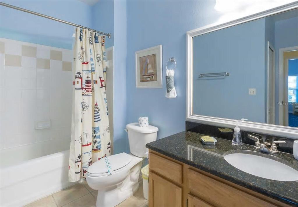 A bathroom features light blue walls, a dark granite vanity, and a nautical-themed shower curtain — 3013 BONFIRE BEACH DRIVE UNIT 201, KISSIMMEE, FL