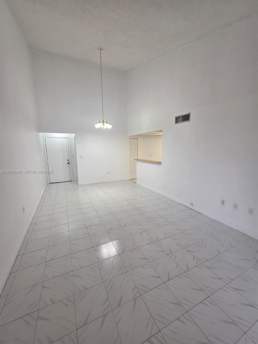 A bright, empty room features white walls, high ceilings, and light-colored tiled flooring — 9429 Fontainebleau Blvd # 33, Miami FL 33172, MIAMI, FL
