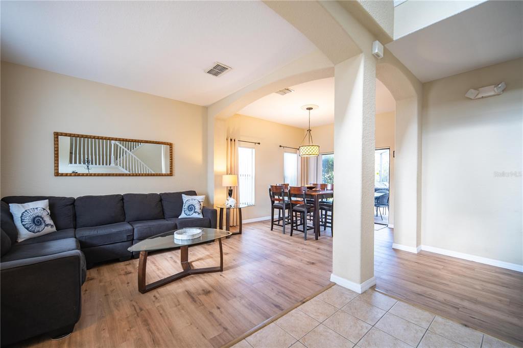 A living room with a dark sectional sofa flows into a dining area with wood flooring — 16609 CARIBBEAN BREEZE WAY, CLERMONT, FL