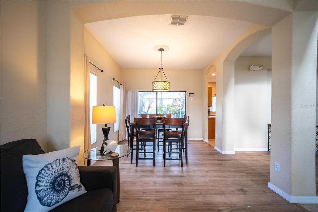 A dining area with a wooden table and chairs sits under a pendant light fixture — 16609 CARIBBEAN BREEZE WAY, CLERMONT, FL