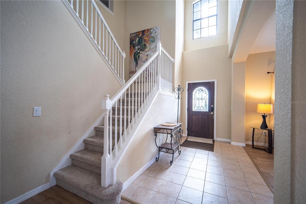 An entryway features a carpeted staircase with white railings, tile flooring, and a front door — 16609 CARIBBEAN BREEZE WAY, CLERMONT, FL