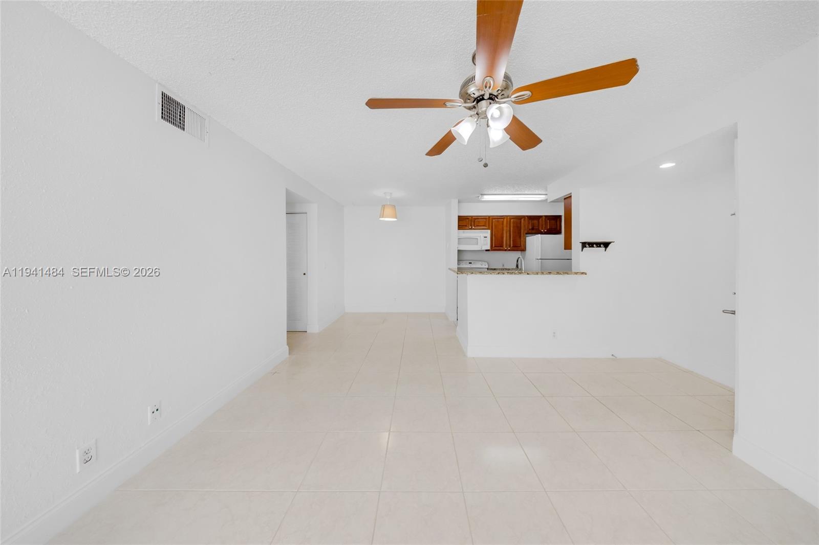 An open-concept living and dining area features white walls, tile flooring, and a kitchen — 2986 S University Dr # 8101, Davie FL 33328, DAVIE, FL