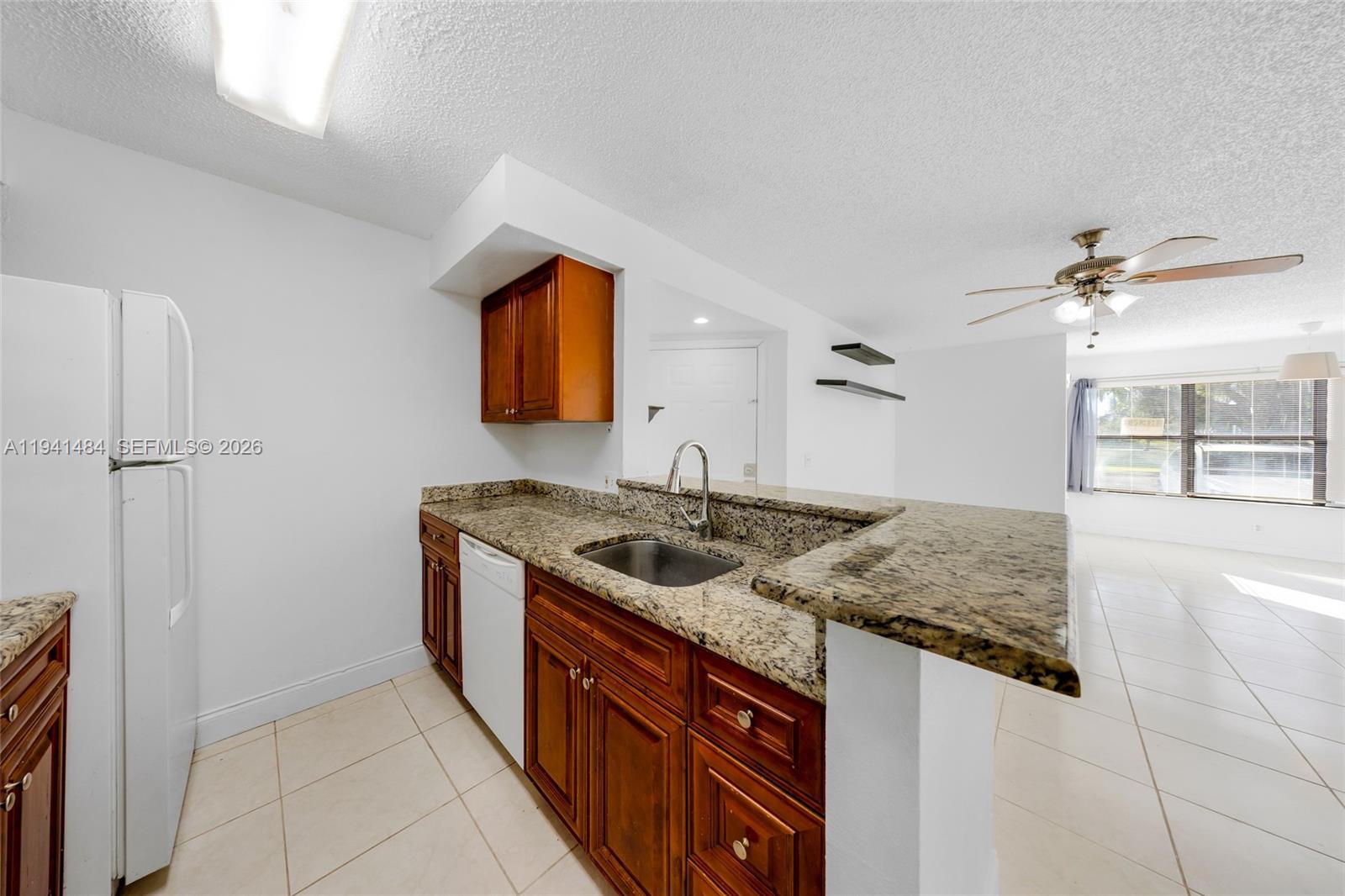 A kitchen features wood cabinets, granite countertops, a stainless steel sink, and white appliances — 2986 S University Dr # 8101, Davie FL 33328, DAVIE, FL