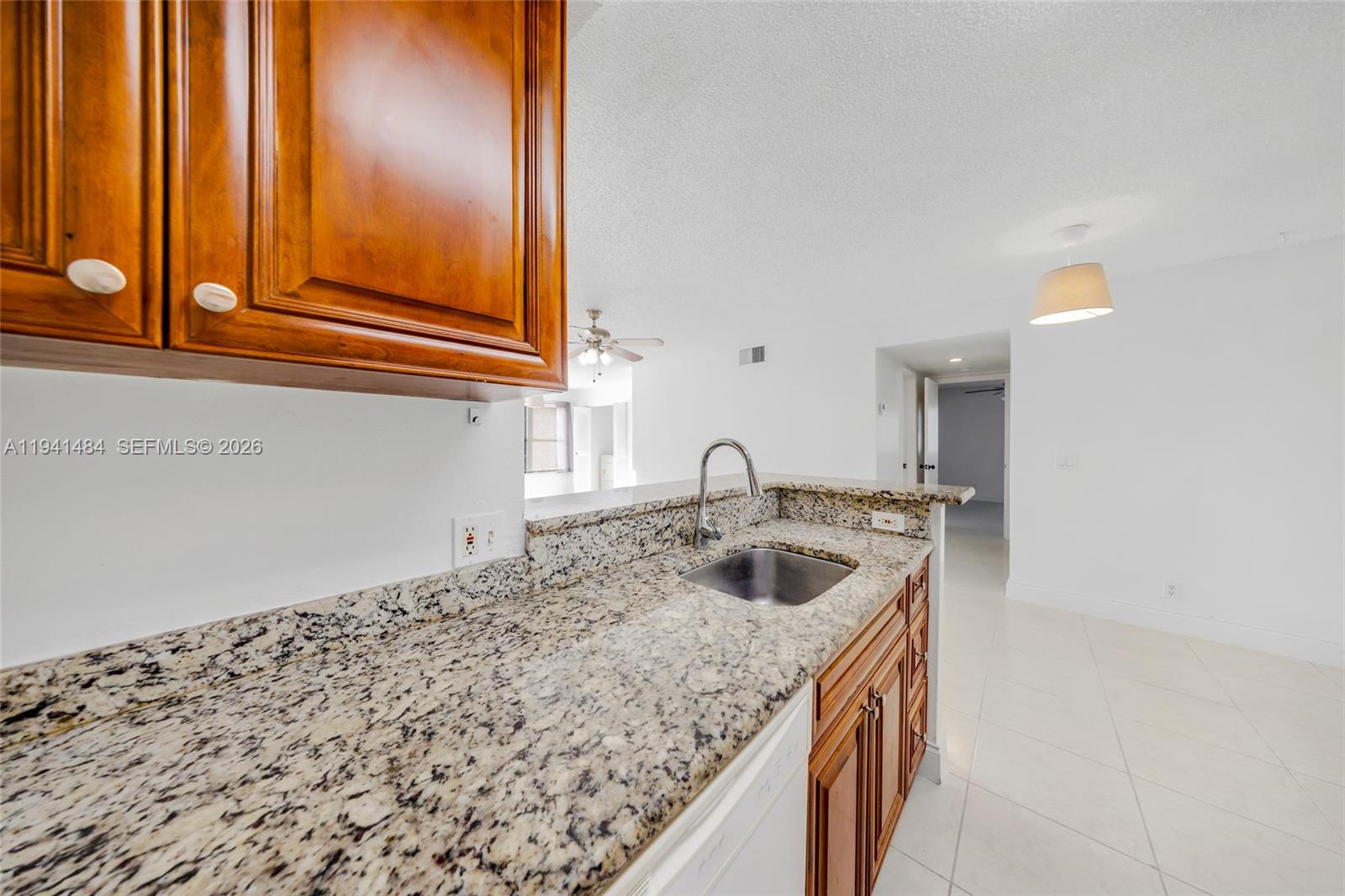 A kitchen features wood cabinets, granite countertops, a stainless steel sink, and tile flooring — 2986 S University Dr # 8101, Davie FL 33328, DAVIE, FL