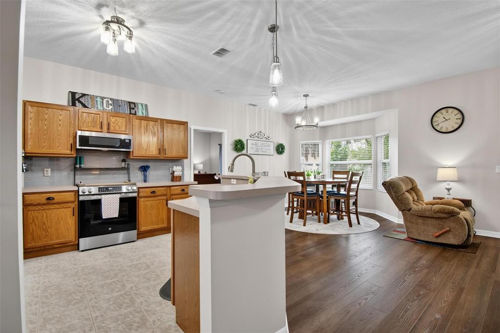 A kitchen with wood cabinets, a stainless steel dishwasher, and an adjacent dining nook — 29 ETHAN ALLEN DRIVE, PALM COAST, FL