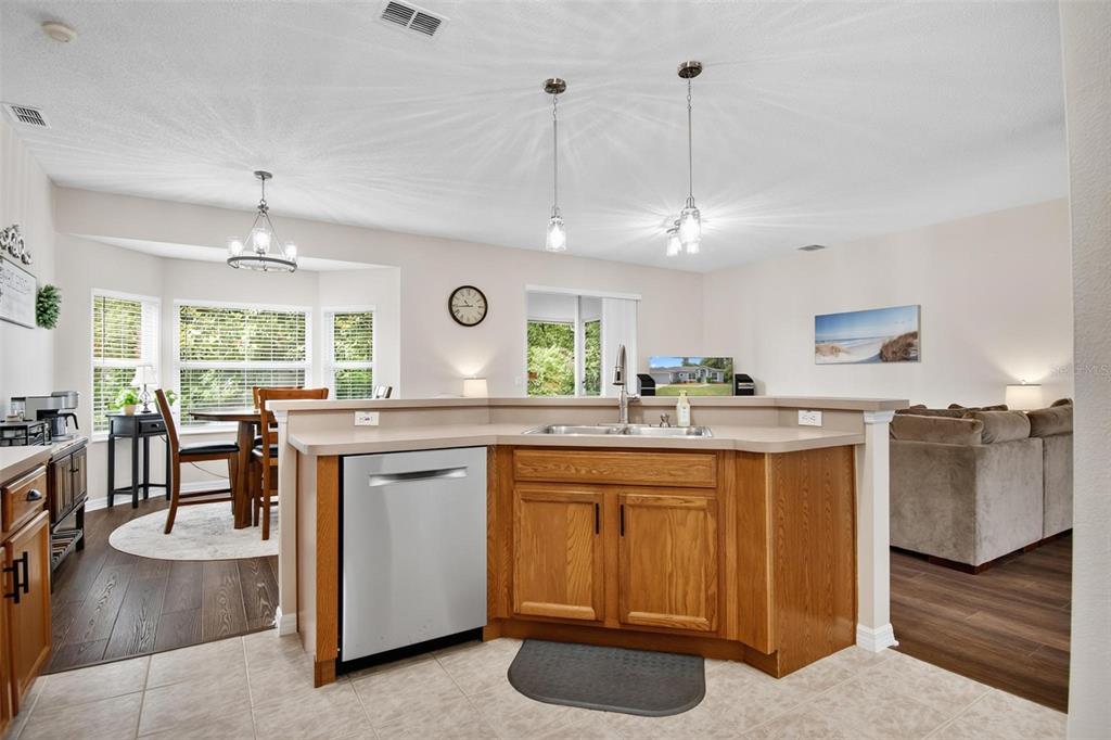 A kitchen with oak cabinets and a dining area with wood floors and a recliner — 29 ETHAN ALLEN DRIVE, PALM COAST, FL