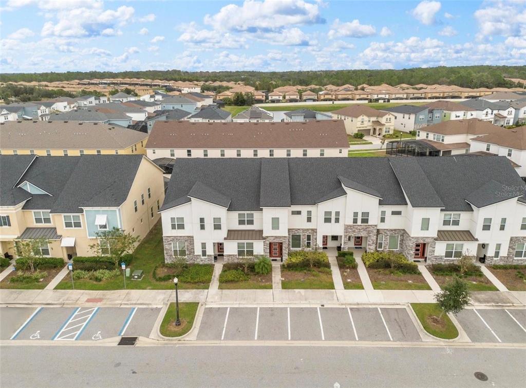 An aerial view shows a row of modern townhomes with parking spaces in the foreground — 2163 COPPER BELL PLACE, KISSIMMEE, FL