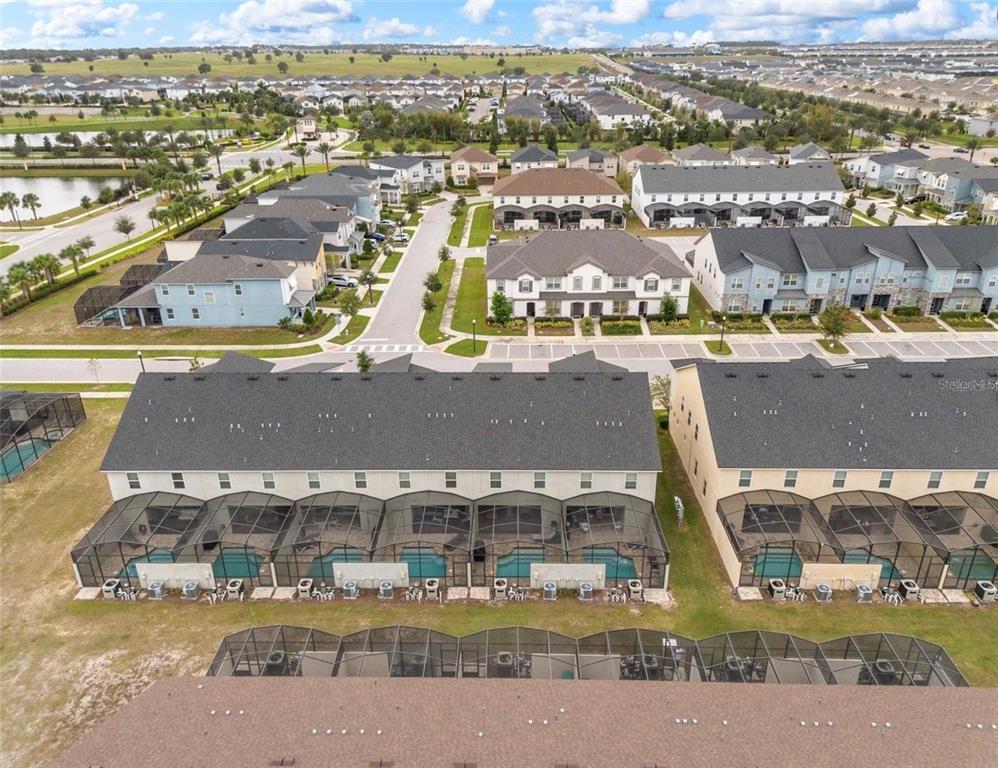 An aerial view shows multiple rows of townhomes with screened-in pools and back patios — 2163 COPPER BELL PLACE, KISSIMMEE, FL