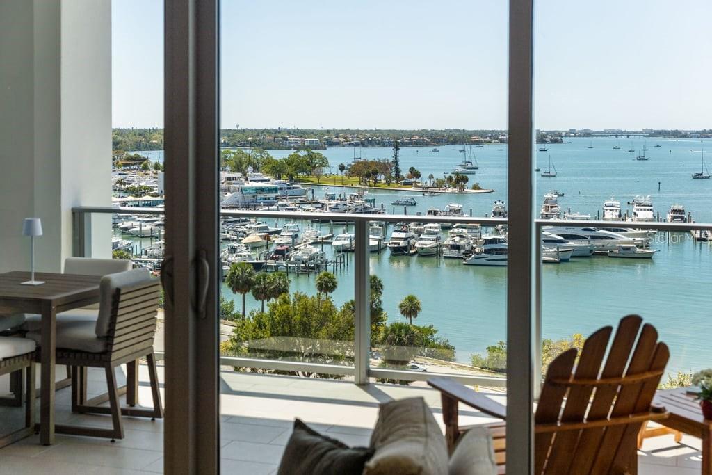 A balcony with outdoor furniture overlooks a marina filled with boats on a sunny day — 1155 N GULFSTREAM AVENUE UNIT 802, SARASOTA, FL