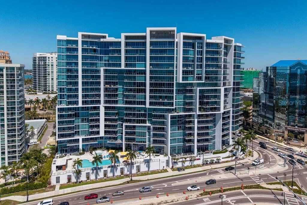 An aerial view of a modern high-rise apartment building with a swimming pool and balconies — 1155 N GULFSTREAM AVENUE UNIT 802, SARASOTA, FL