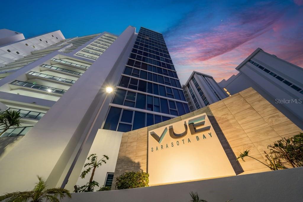 Low-angle exterior view of the Vue Sarasota Bay high-rise condominium building at dusk — 1155 N GULFSTREAM AVENUE UNIT 802, SARASOTA, FL