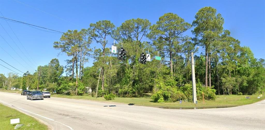 A street intersection features traffic lights, tall pine trees, and a clear blue sky — 0 AGRICULTURAL CENTER DRIVE, ST AUGUSTINE, FL