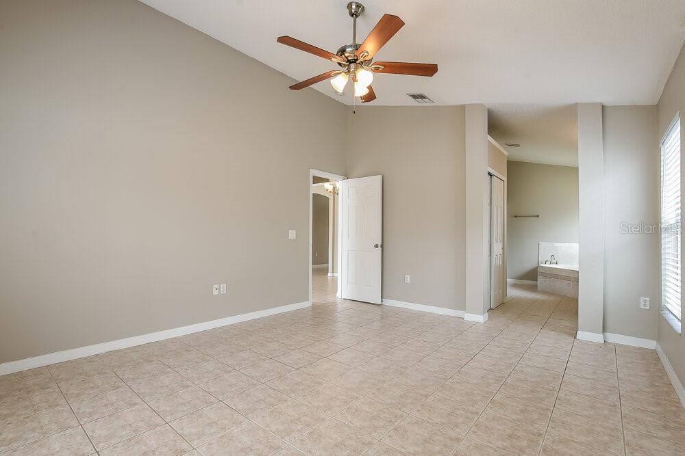 A spacious room with beige walls, tile flooring, a ceiling fan, and an open doorway — 4616 FALCON AVENUE, KISSIMMEE, FL