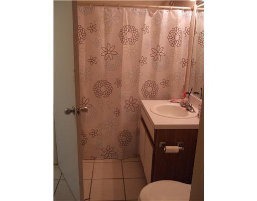A bathroom features a floral shower curtain, a vanity with a sink, and tiled flooring — 6355 La Costa Drive # L, Boca Raton FL 33433, BOCA RATON, FL