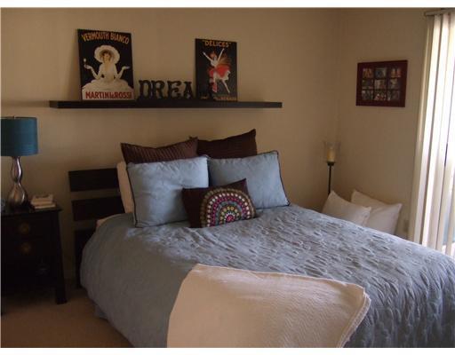 A bedroom features a bed with blue bedding, a floating shelf, and a bedside lamp — 6355 La Costa Drive # L, Boca Raton FL 33433, BOCA RATON, FL