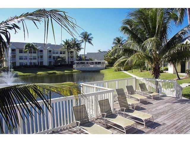 A wooden deck with lounge chairs overlooks a pond, a fountain, and apartment buildings — 6355 La Costa Drive # L, Boca Raton FL 33433, BOCA RATON, FL