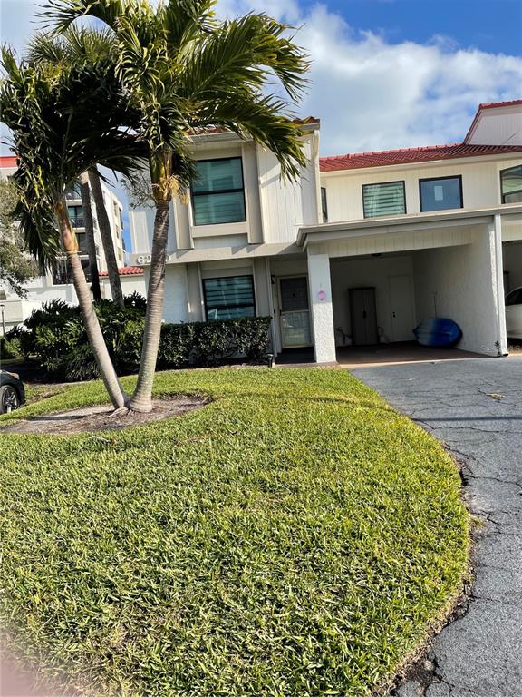 A two-story townhouse exterior features a palm tree, a covered carport, and a grassy lawn — 6260 SUN BOULEVARD UNIT 1, ST PETERSBURG, FL