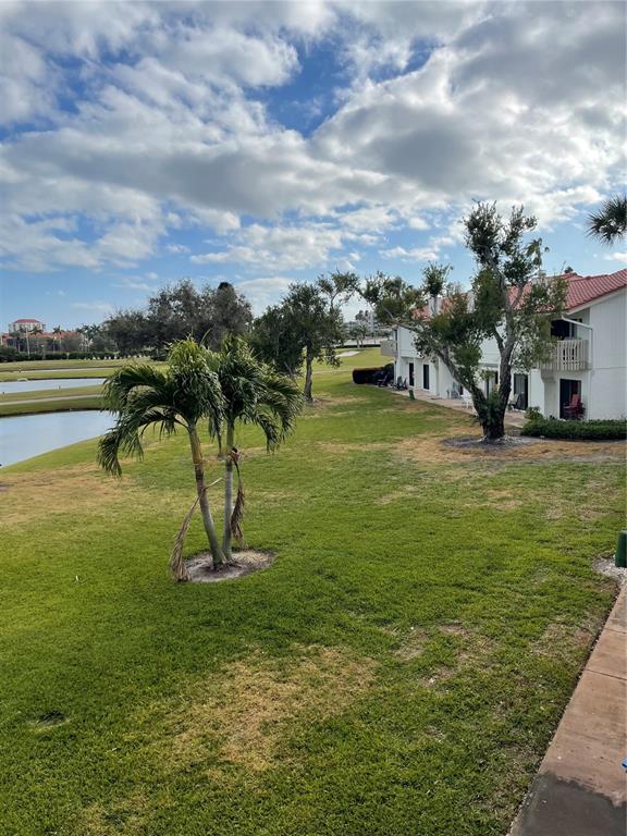 A grassy lawn with palm trees and a pond sits beside a multi-story building — 6260 SUN BOULEVARD UNIT 1, ST PETERSBURG, FL