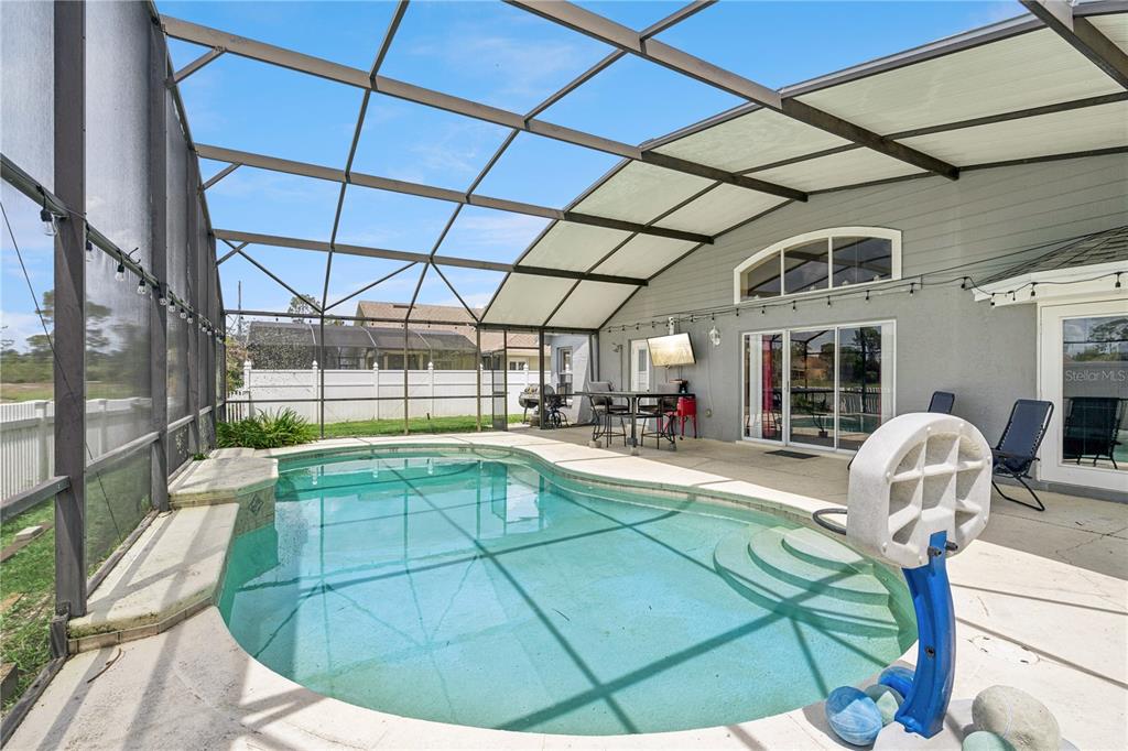 A screened-in patio features a swimming pool with steps and a basketball hoop — 12422 MARLEIGH COURT, ORLANDO, FL