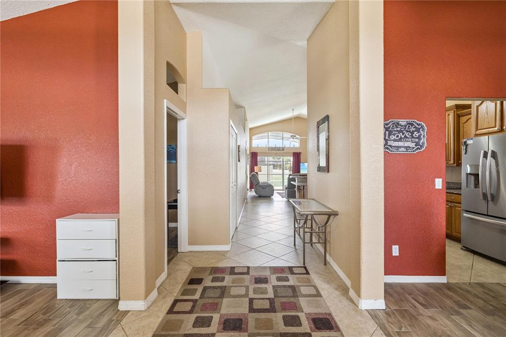 A tiled entryway leads into a living area with vaulted ceilings and red accent walls — 12422 MARLEIGH COURT, ORLANDO, FL