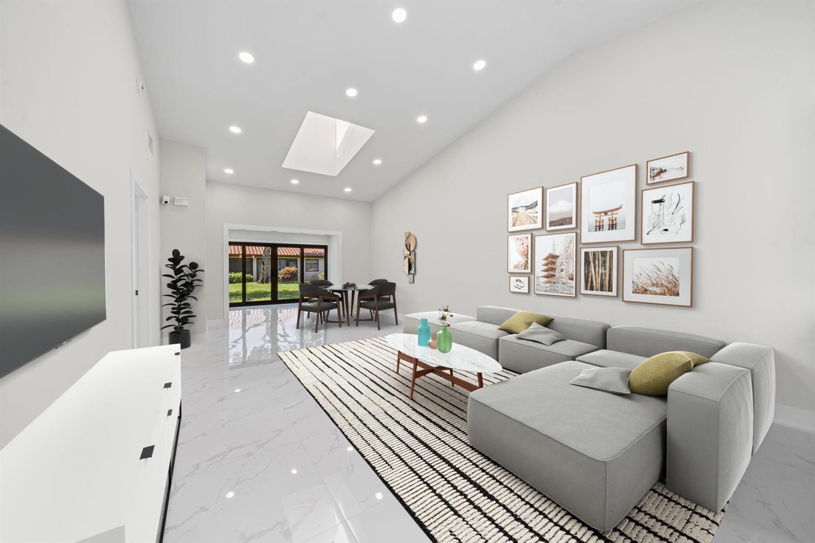 A modern living room features a gray sectional sofa, a striped rug, and a dining area — 6371 Kings Gate Circle, Delray Beach FL 33484, DELRAY BEACH, FL