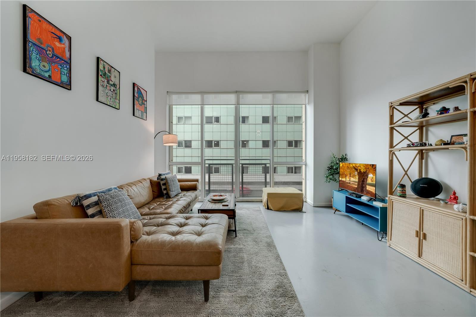 A living room features a tan leather sectional, a blue media console, and a tall shelf — 253 NE 2nd St # 228, Miami FL 33132, MIAMI, FL