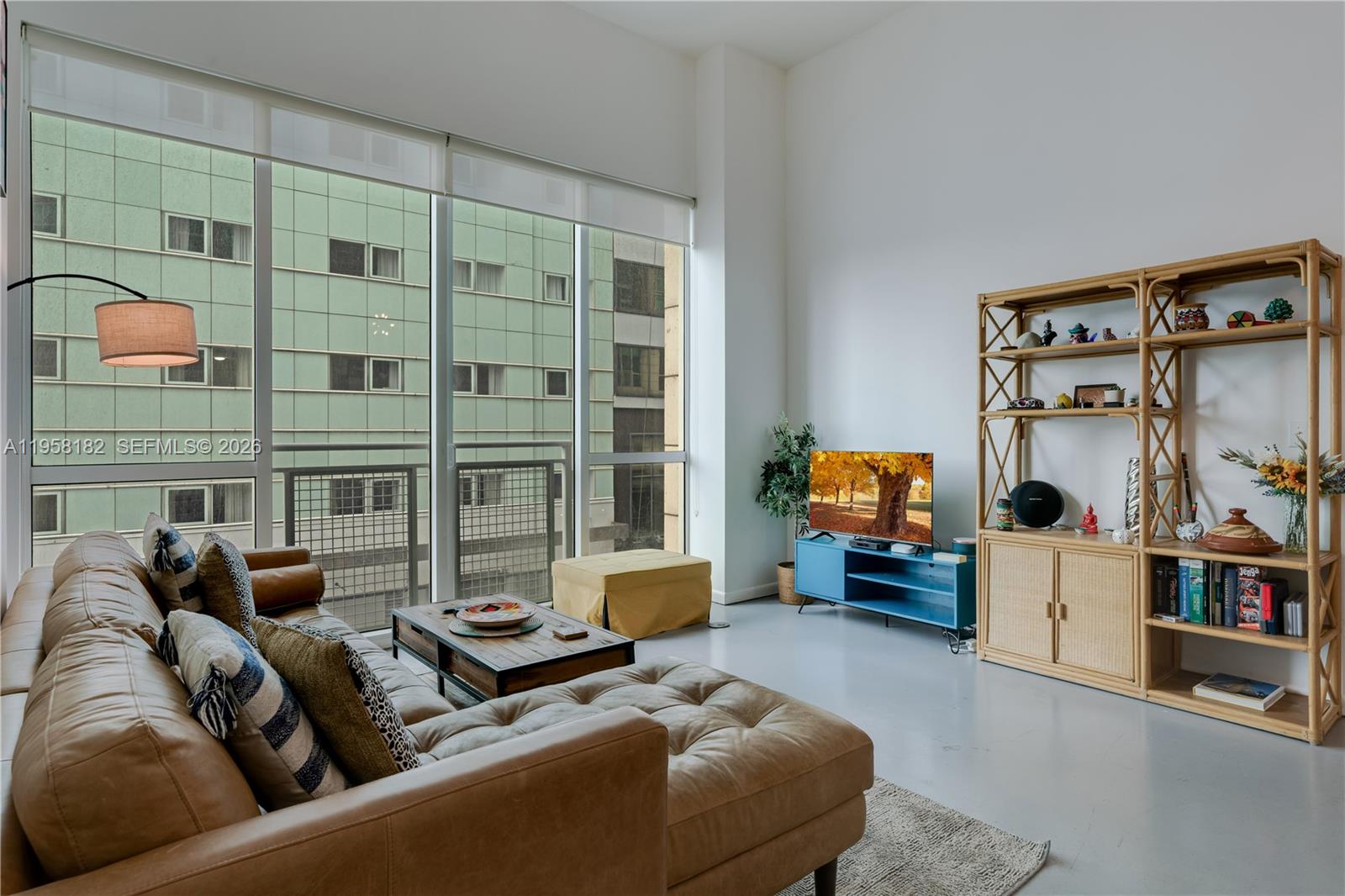 A living room features a leather sectional, a blue media console, and large floor-to-ceiling windows — 253 NE 2nd St # 228, Miami FL 33132, MIAMI, FL