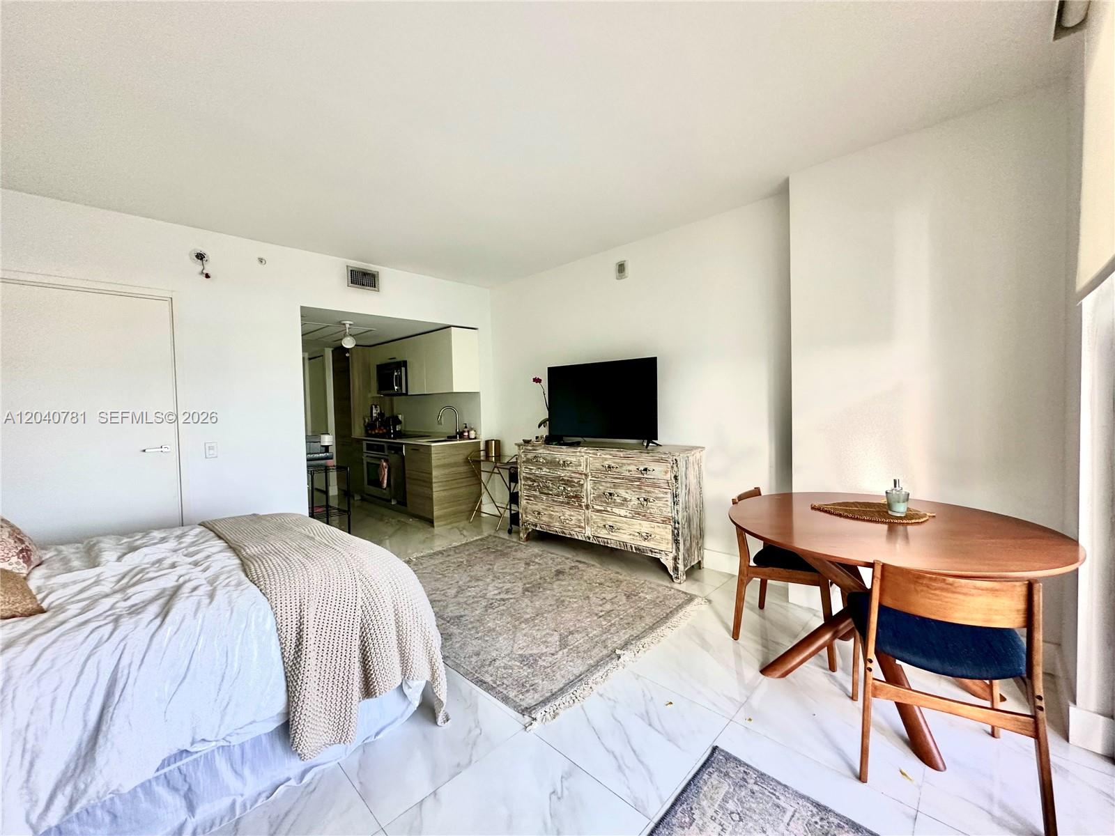 A studio apartment features a bed, a dining table, a television, and a small kitchen — 1300 Brickell Bay Dr # 2106, Miami FL 33131, MIAMI, FL