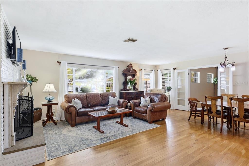 A living room with hardwood floors, a brick fireplace, leather furniture, and an adjacent dining area — 401 28TH STREET W, BRADENTON, FL