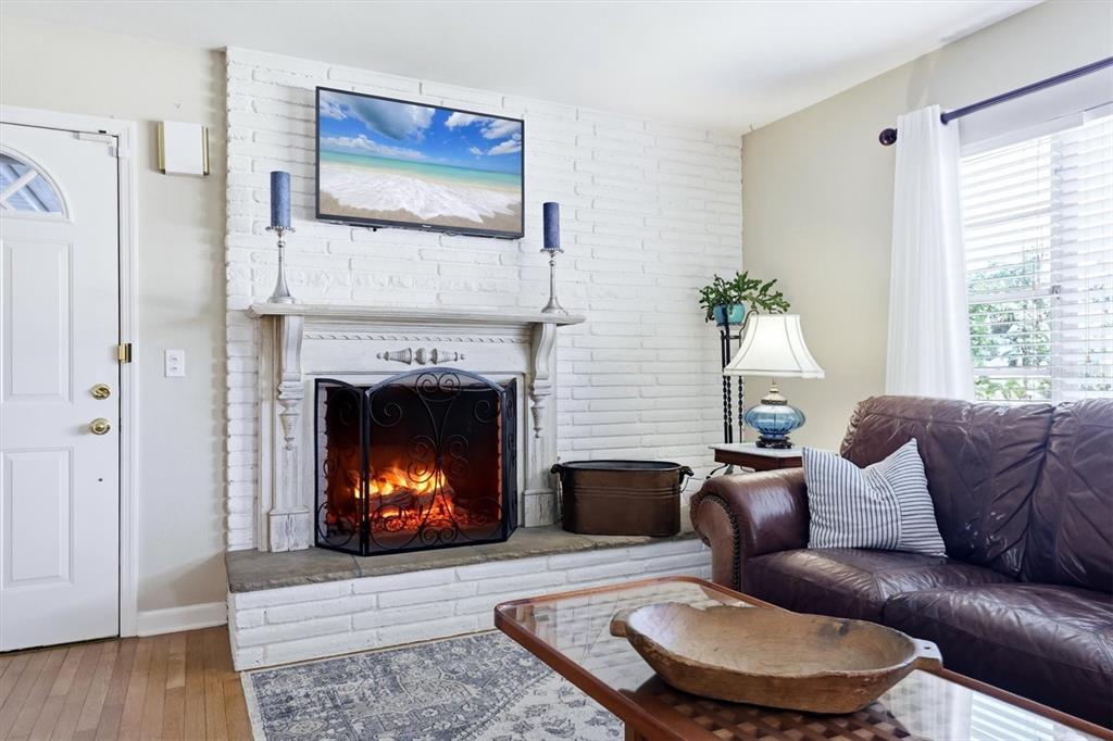 A living room features a white brick fireplace, a mounted television, and a brown leather sofa — 401 28TH STREET W, BRADENTON, FL
