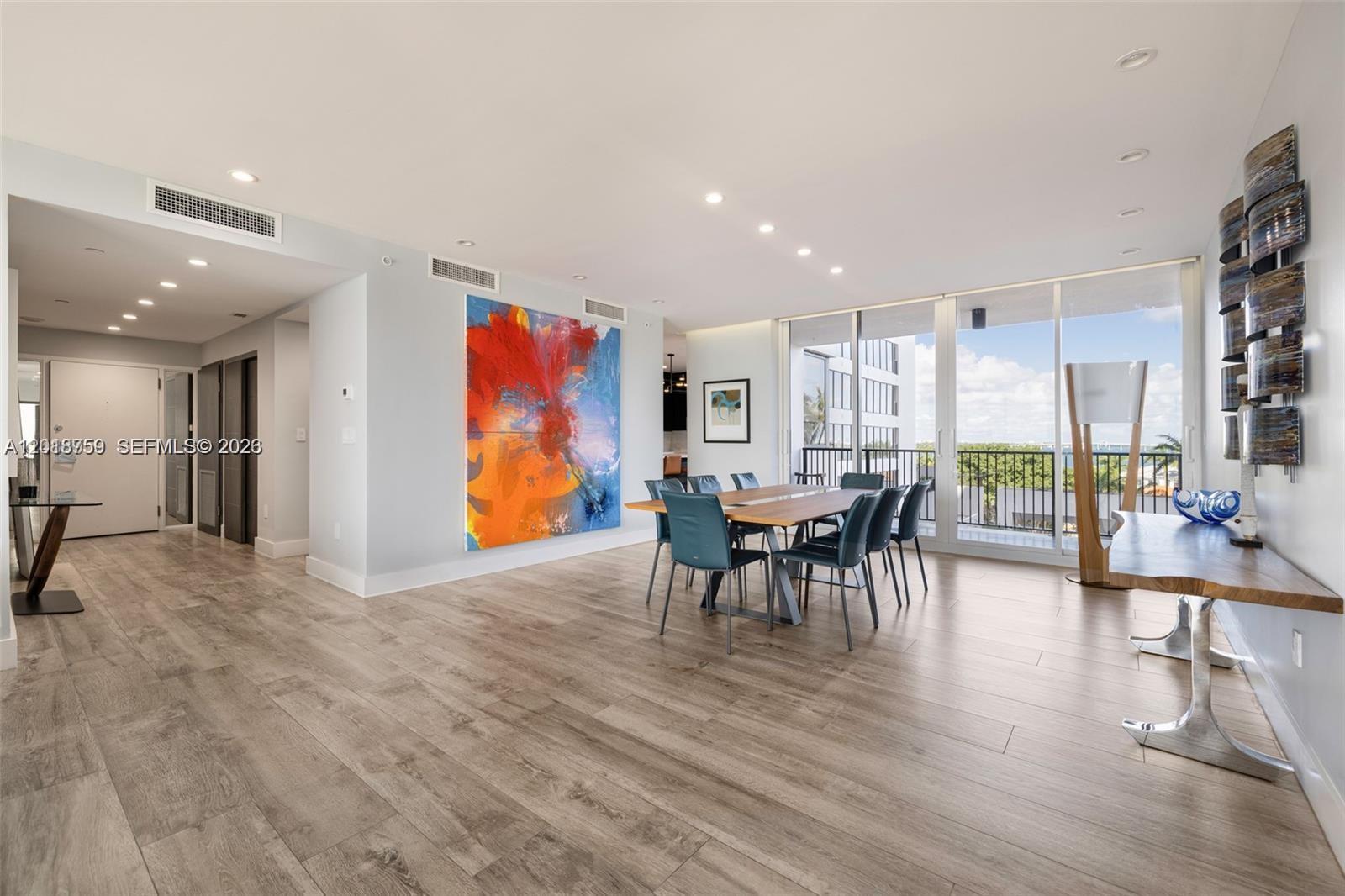 A dining area features a large abstract painting, wood-look flooring, and floor-to-ceiling glass doors — 1000 Venetian Way # 502, Miami FL 33139, MIAMI, FL