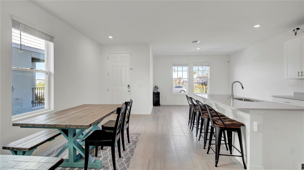 A dining area with a wooden table and a kitchen island with bar stools — 4704 HOMESTEAD TRAIL, ST CLOUD, FL
