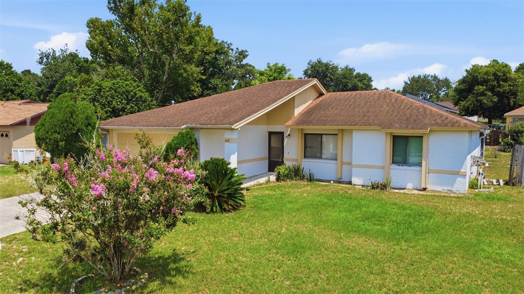 A single-story house with a brown shingled roof, white stucco walls, and a front lawn — 1418 CATALINA BOULEVARD, DELTONA, FL