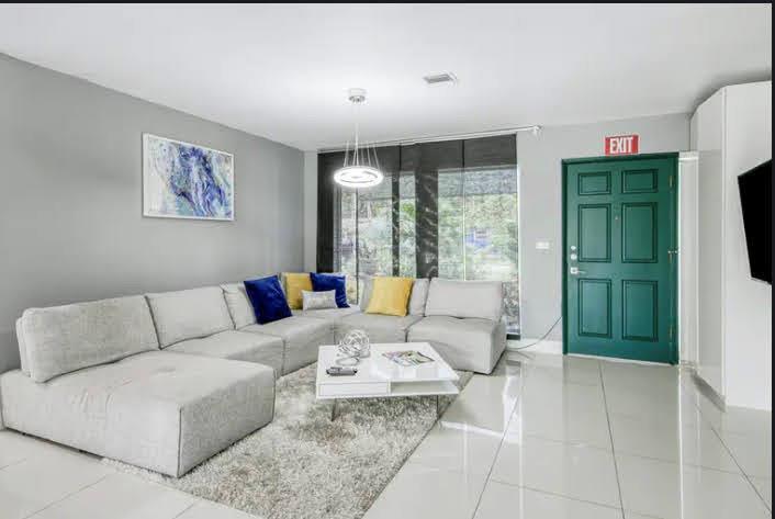 A living room features a large gray sectional sofa, a white coffee table, and a green door — 1905 N 45th Avenue, Hollywood FL 33021, HOLLYWOOD, FL