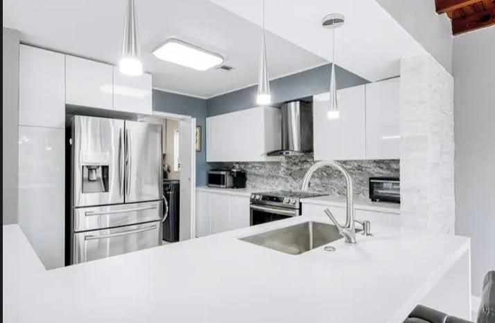 A modern kitchen features white cabinetry, stainless steel appliances, and a white quartz island countertop — 1905 N 45th Avenue, Hollywood FL 33021, HOLLYWOOD, FL