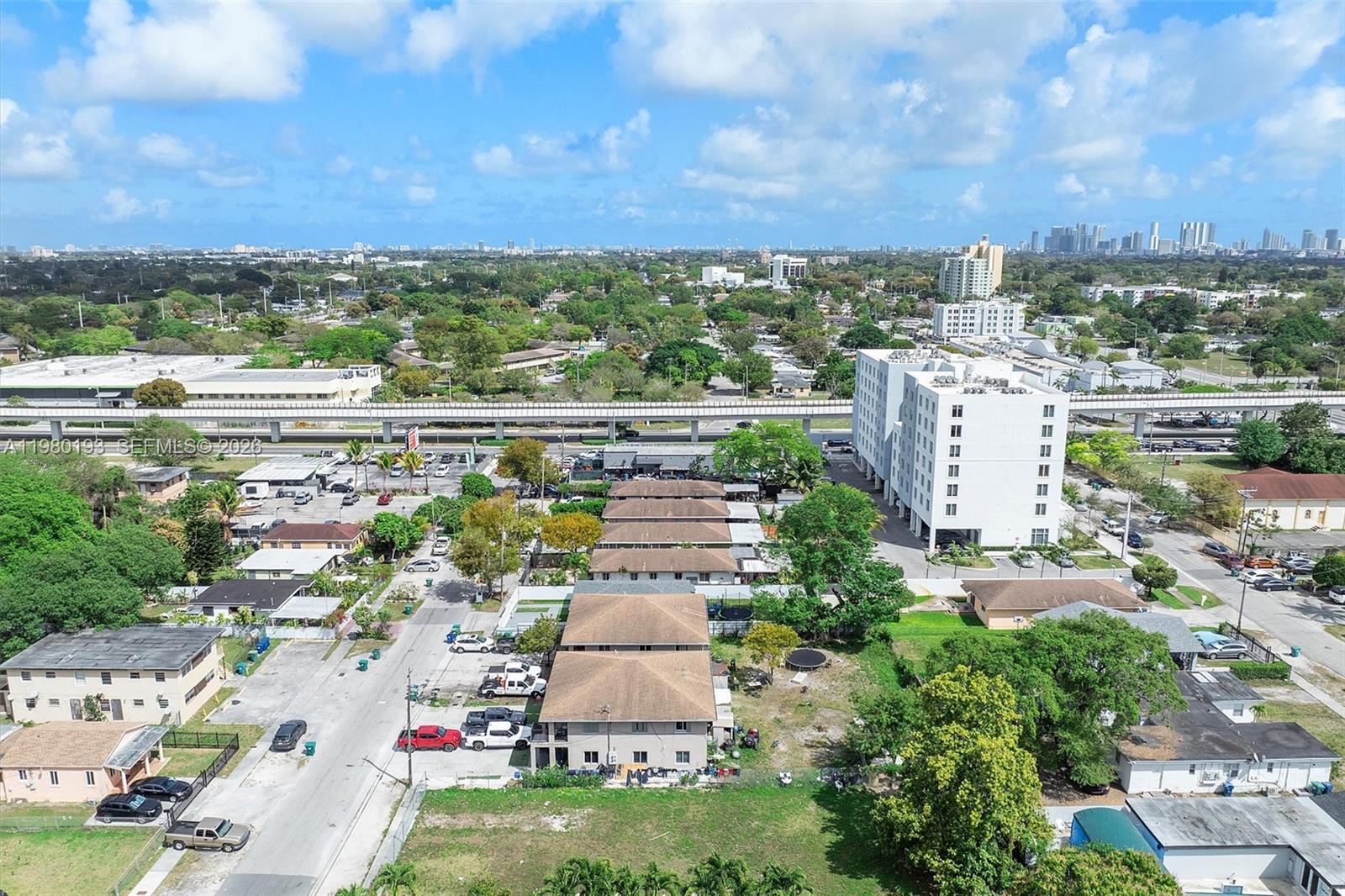 An aerial view shows a residential neighborhood with multi-story apartment buildings and a nearby elevated train track — 2780 NW 56th St, Miami FL 33142, MIAMI, FL