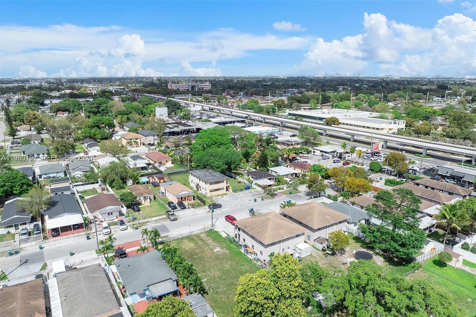 An aerial view shows a residential neighborhood with houses, trees, and an elevated train track — 2780 NW 56th St, Miami FL 33142, MIAMI, FL