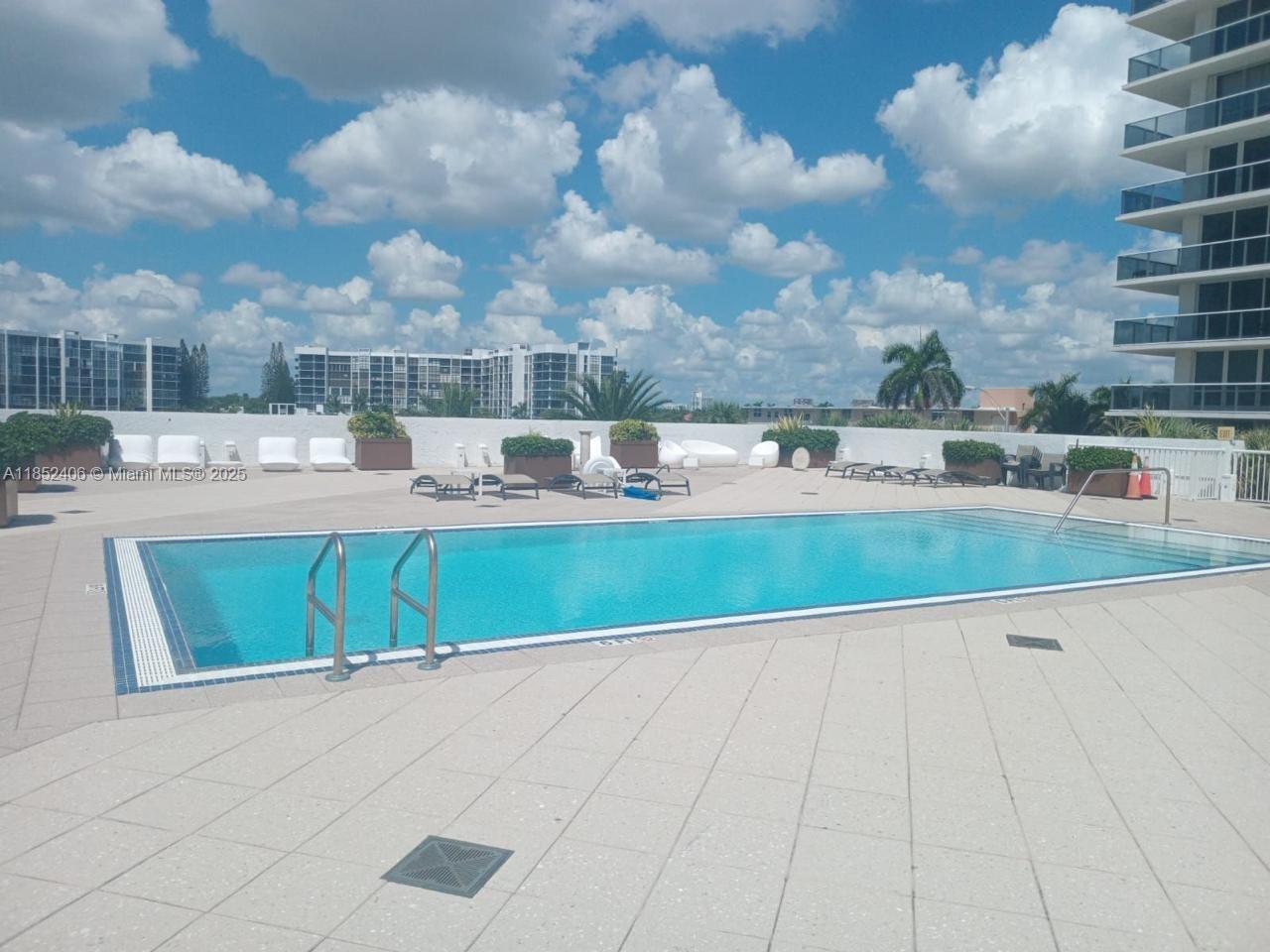 An outdoor swimming pool with lounge chairs on a paved deck under a cloudy sky — 2751 S Ocean Dr, Hollywood FL 33019, HOLLYWOOD, FL