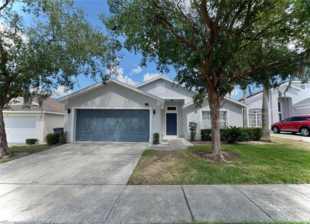 A single-story house with a gray exterior, a two-car garage, and a front walkway — 154 CASTLEMAIN CIRCLE, DAVENPORT, FL