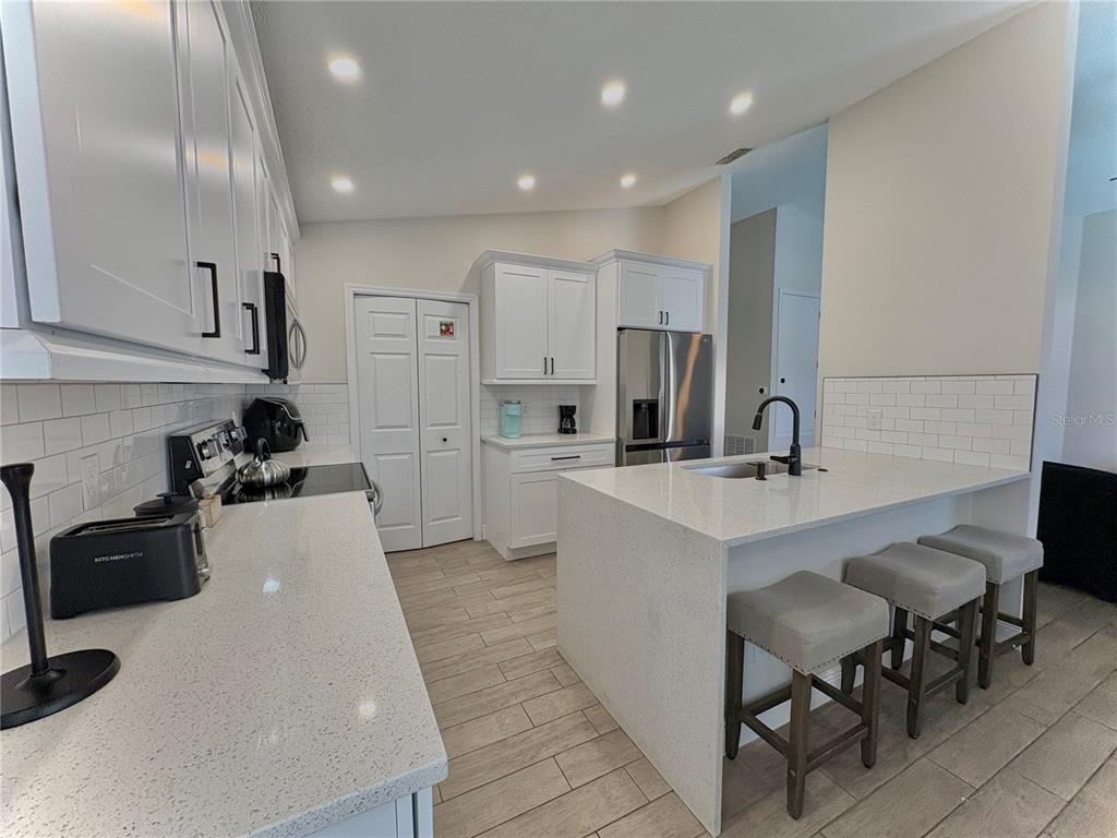A modern kitchen features white cabinets, quartz countertops, a center island, and subway tile backsplash — 154 CASTLEMAIN CIRCLE, DAVENPORT, FL