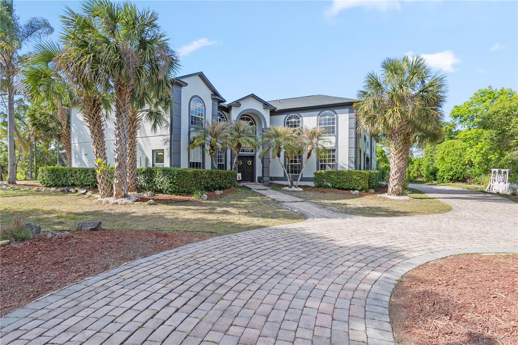 A two-story house with a paved driveway and palm trees in the front yard — 1140 GALLANT FOX WAY, CHULUOTA, FL