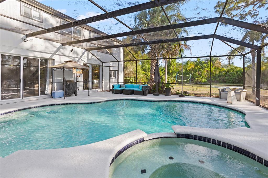 A screened-in patio features a swimming pool, a hot tub, and outdoor seating — 1140 GALLANT FOX WAY, CHULUOTA, FL