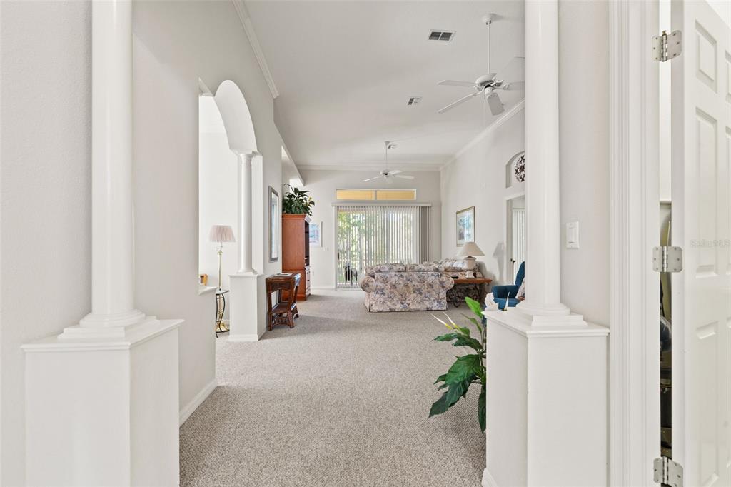 A view through a doorway into a carpeted living room with white columns and vaulted ceilings — 10199 HOLLY BERRY DRIVE, WEEKI WACHEE, FL