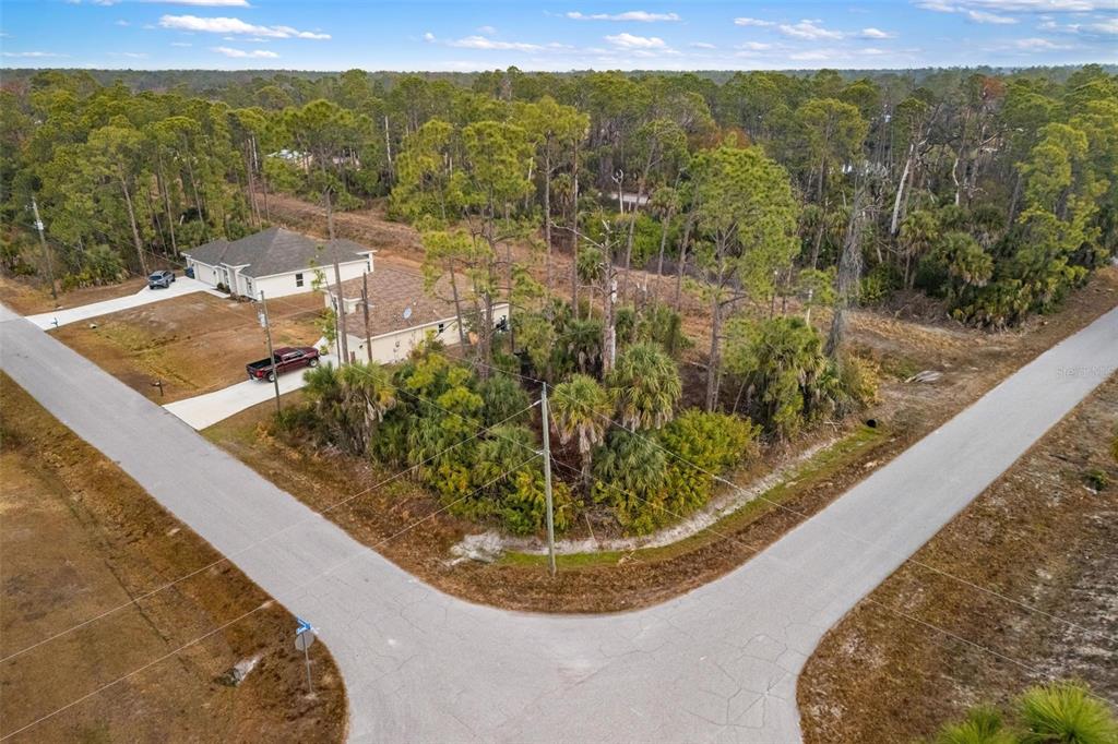 An aerial view shows a corner lot with dense vegetation next to a residential house — DUMA WAY, NORTH PORT, FL