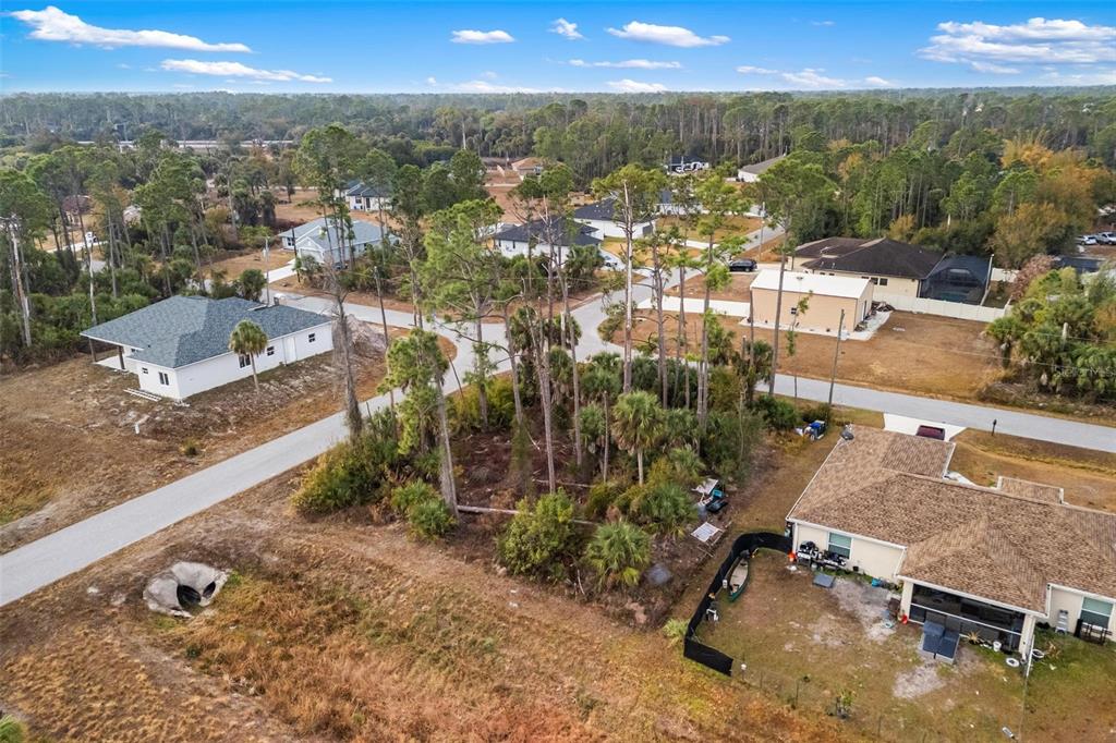 An aerial view shows a vacant wooded lot situated between several residential houses and roads — DUMA WAY, NORTH PORT, FL